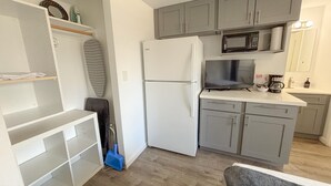 Eine kompakte Küche mit Kühlschrank, Mikrowelle und Kaffeemaschine auf der Arbeitsfläche.