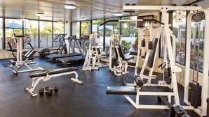 A gym with treadmills, weight machines, and dumbbells. - Lovely Luana Waikiki Studio | Private Lanai (Honolulu)