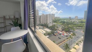 A balcony with a view of a cityscape, including high-rise buildings and a parking area. - Trendy Hawaiian Monarch Studio | Ocean View | Pool (Honolulu)