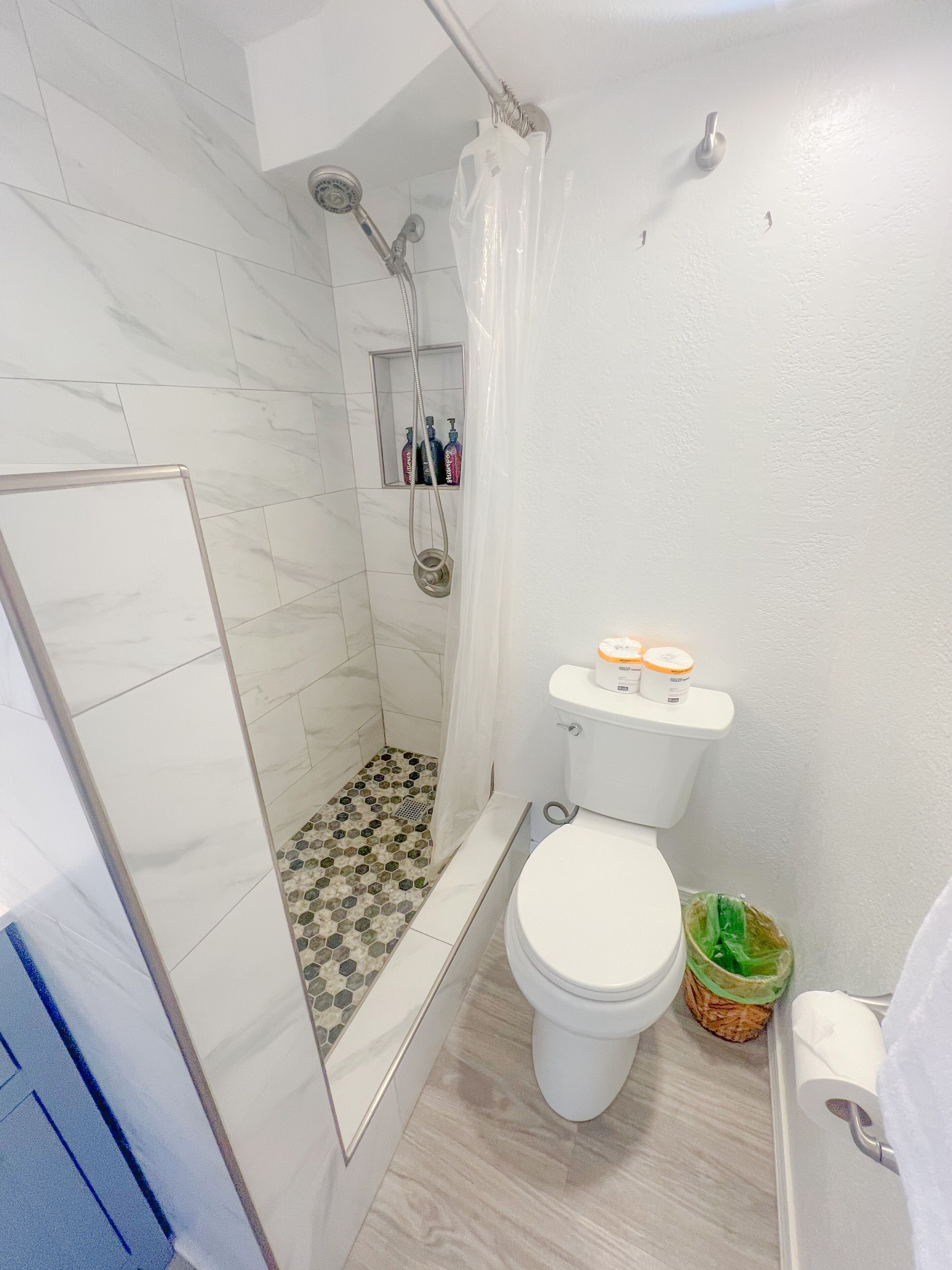 A bathroom with a shower, toilet, and a small sink area.