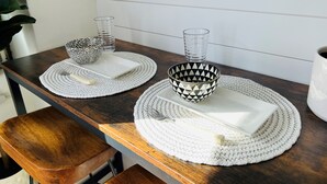 A wooden table with two white placemats, a black and white patterned bowl, a clear glass, and a white plate. - Modern Surf Chic Studio at Hawaiian Monarch | Pool (Honolulu)