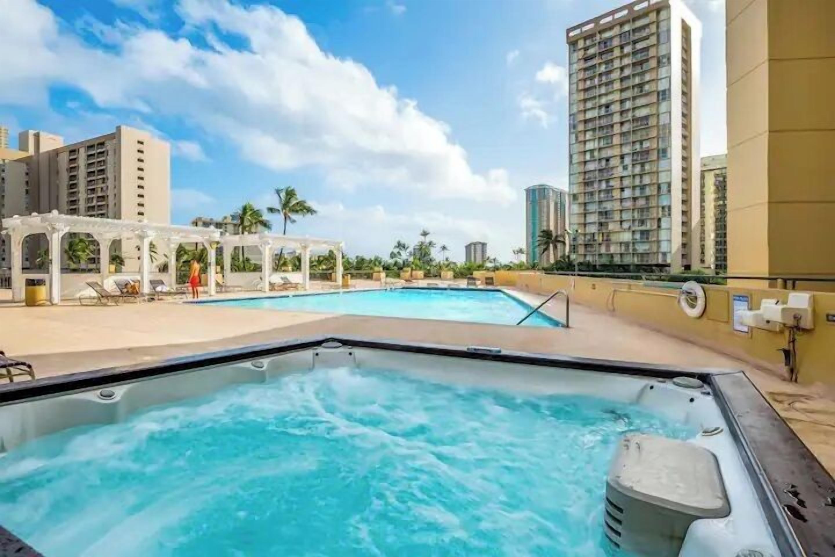 Ein Bereich mit Whirlpool, Pool, Liegestühlen und einer Pergola.