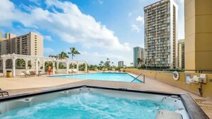 A hot tub area with a pool, lounge chairs, and a pergola. - Modern Surf Chic Studio at Hawaiian Monarch | Pool (Honolulu)