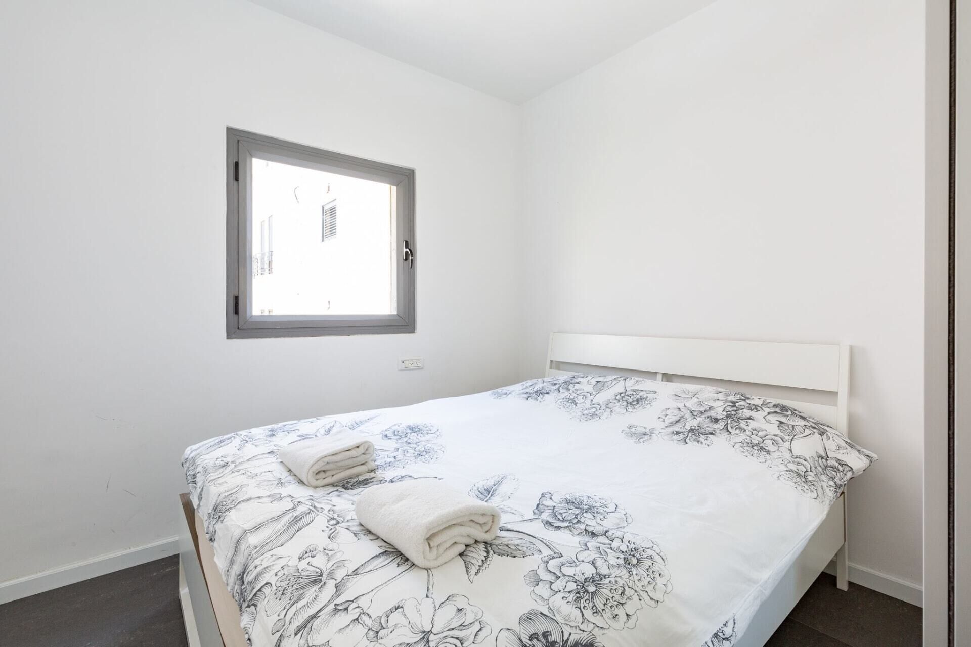 A bedroom with a bed, a window, and a door.