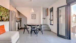 Ein modernes Apartment mit Essbereich, Küche und einem Balkon mit Blick auf die Stadt.