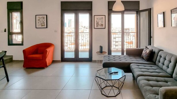Ein modernes Wohnzimmer mit einem grauen Sofa, einem roten Sessel und einem Glastisch.