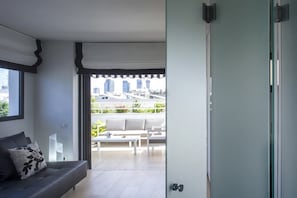 Uma sala de estar moderna com um sofá cinzento e vista para uma varanda com mobiliário de exterior.