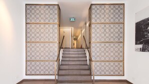 A staircase with a patterned wall divider, a sign indicating an exit, and a framed picture on the wall. - Pines Belle - Two Bedroom Apartment, Sleeps 4 (Tel Aviv-Yafo)