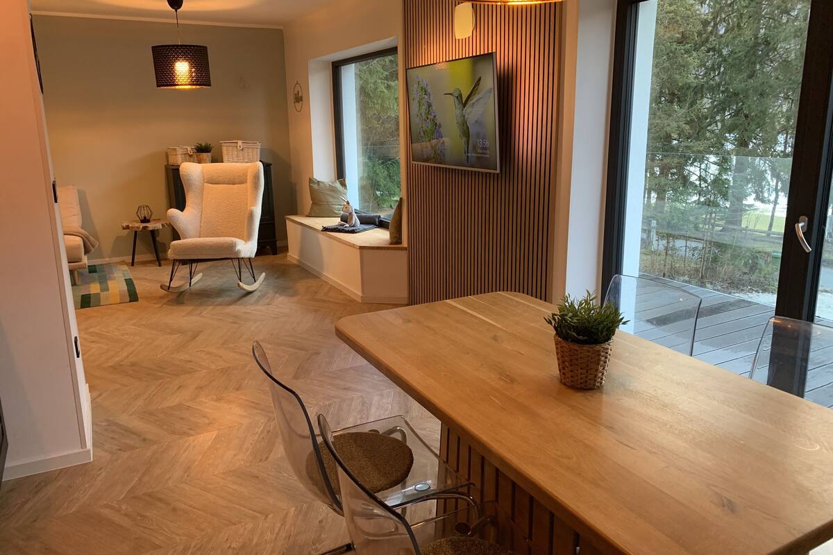 Un comedor moderno con una mesa de madera, sillas de vidrio transparente y una lámpara colgante.
