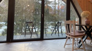 A room with a large sliding glass door leading to an outdoor deck with chairs and a table. - Pine Tree Holiday House (Kranjska Gora)