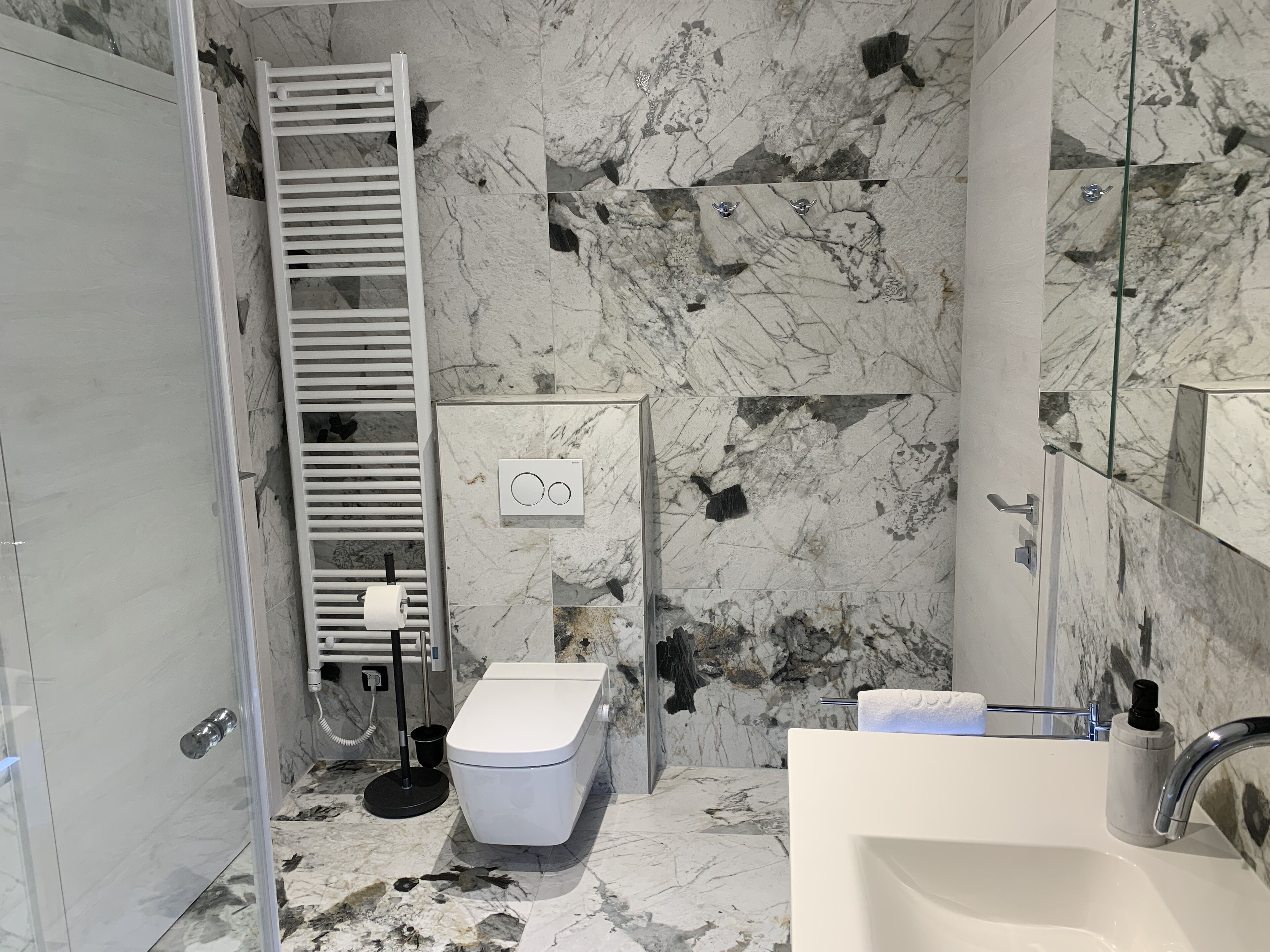 Un baño con inodoro, lavamanos y toallero.