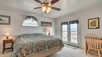 Une chambre à coucher avec un lit, un ventilateur de plafond, une chaise, une lampe, une fenêtre et une porte.