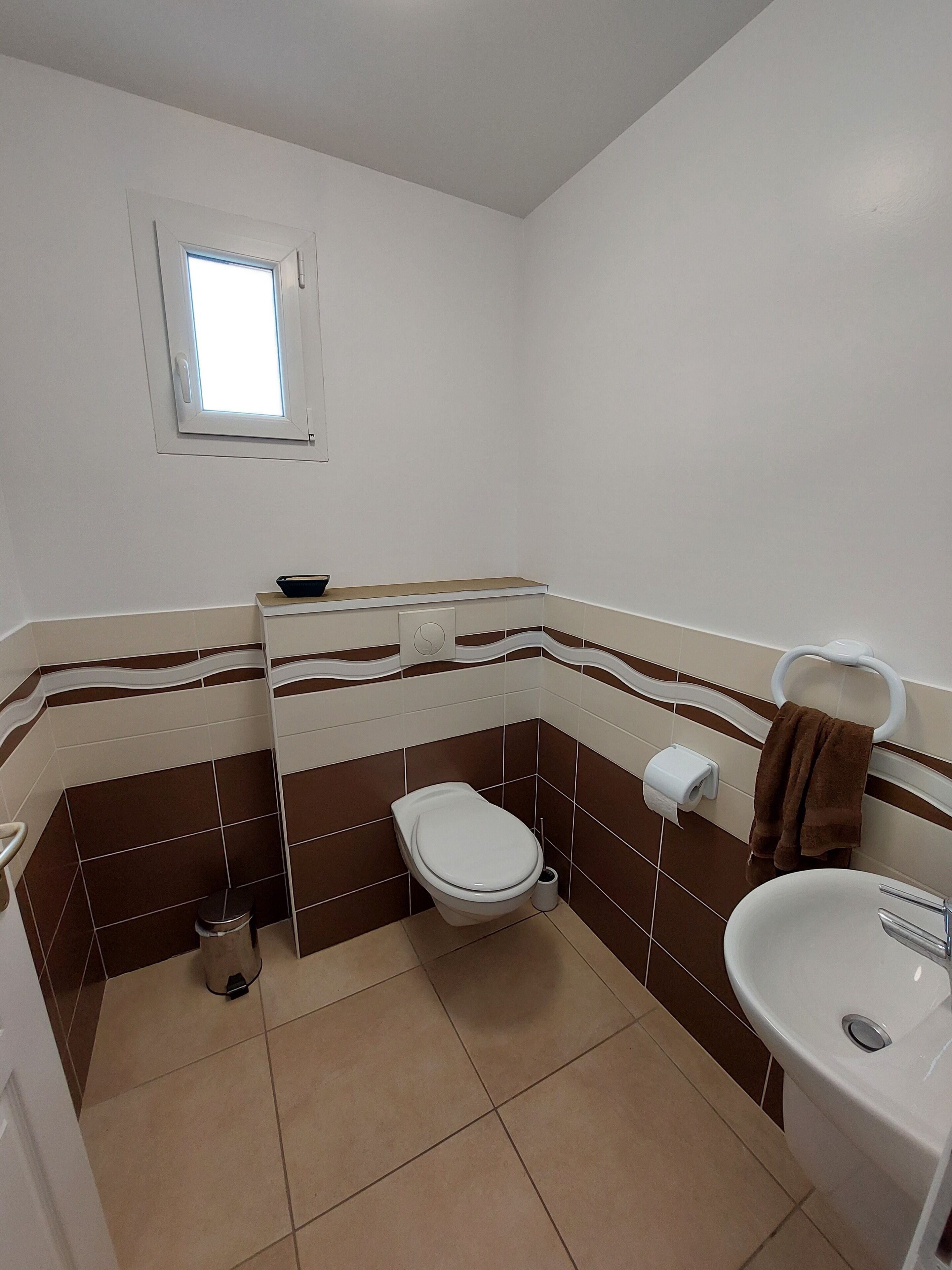 Une salle de bain avec des toilettes, un lavabo et une petite fenêtre.