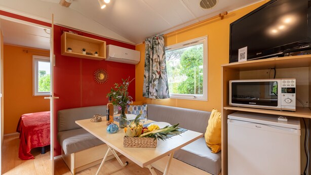 A compact living space with a kitchenette, a dining area, and a seating area. - Estrellus, mobile home in the vineyard (Hyères)