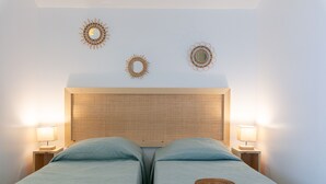 A bedroom with two beds, a woven headboard, bedside lamps, and decorative wall mirrors. - Mon Rêve, fisherman's cottage feet in the water (Hyères)