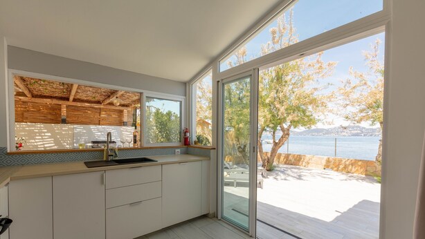 A modern kitchen with a large window and a view of a waterfront. - Mon Rêve, fisherman's cottage feet in the water (Hyères)