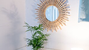 Ein Badezimmer-Waschtisch mit Spiegel, einer Topfpflanze und einem Schild mit der Aufschrift 'Es ist so schön, wieder zu Hause zu sein'.