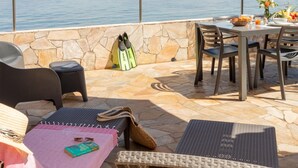 Eine Terrasse im Freien mit Steinfliesen, Korbmöbeln und einem Tisch, der zum Essen gedeckt ist.