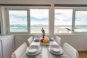 A dining area with a table set for four, overlooking a coastal view with boats and a pier. - La Roche, cottage on the waterfront in La Madrague (Hyères)