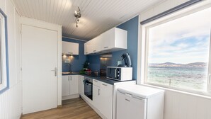 Cocina compacta con muebles blancos, microondas y cafetera.