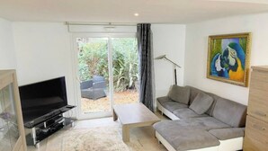 Een woonkamer met een bank, een televisie, een salontafel en een schilderij aan de muur.
