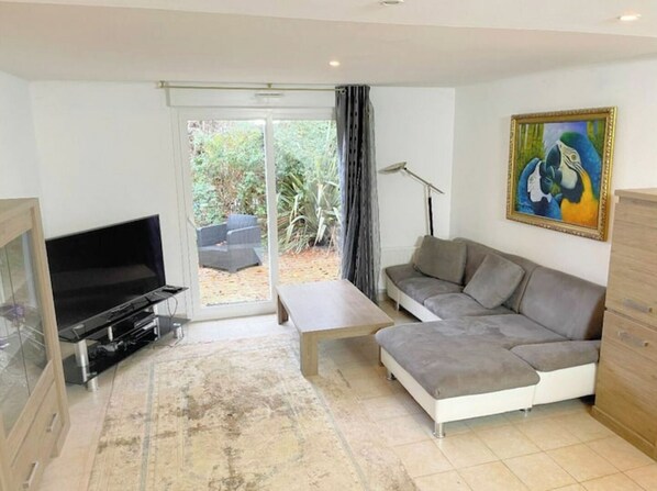 Un salon avec un canapé, un téléviseur, une table basse et un tableau accroché au mur.