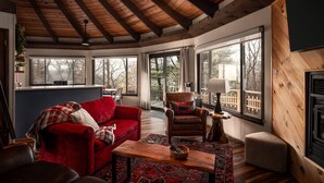 Una sala de estar acogedora con un sofá rojo, una mesa de centro de madera y un sillón de cuero.