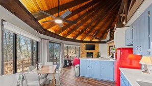 Una cocina amplia con vigas de madera, un comedor con mesa y sillas, y ventanas grandes que ofrecen vistas al exterior.