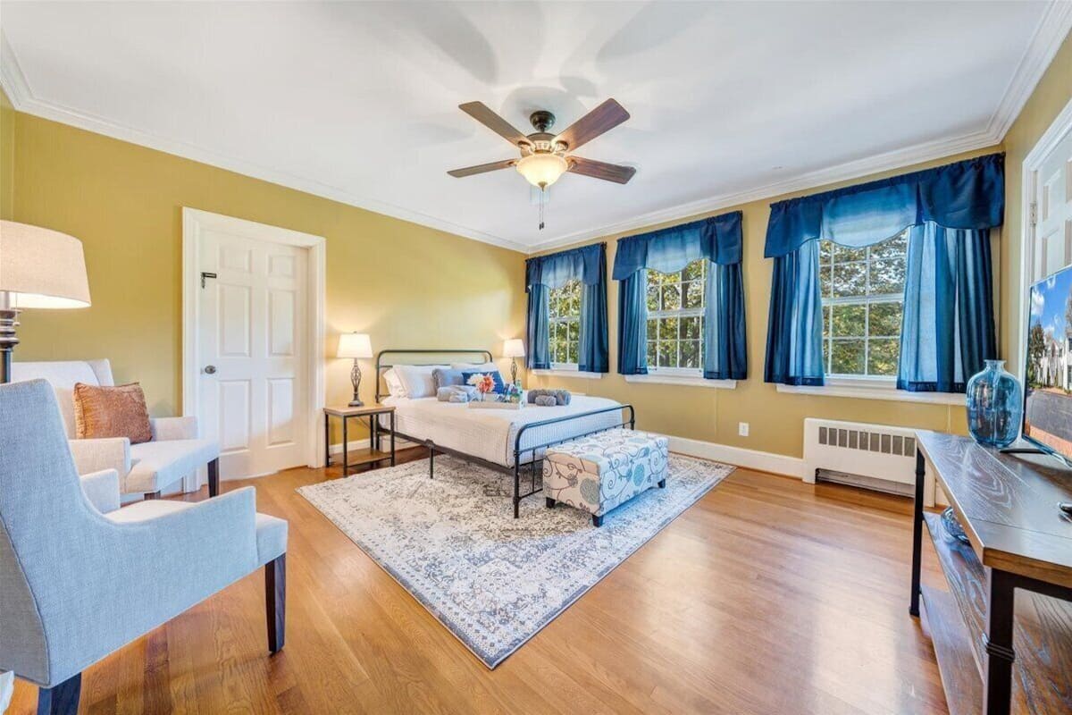 A bedroom with a bed, a desk, a chair, and a ceiling fan.