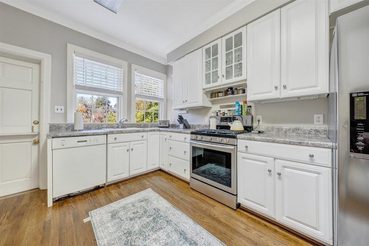 A modern kitchen with white cabinetry, a built-in oven, and a refrigerator.