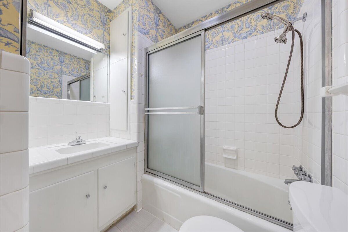 Een badkamer met douche, toilet en wastafel.