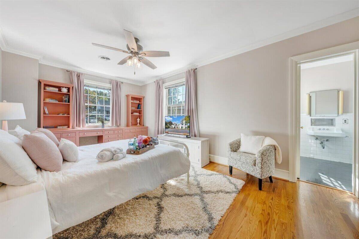 A bedroom with a bed, bedside tables, a vanity, a chair, and a window with curtains.