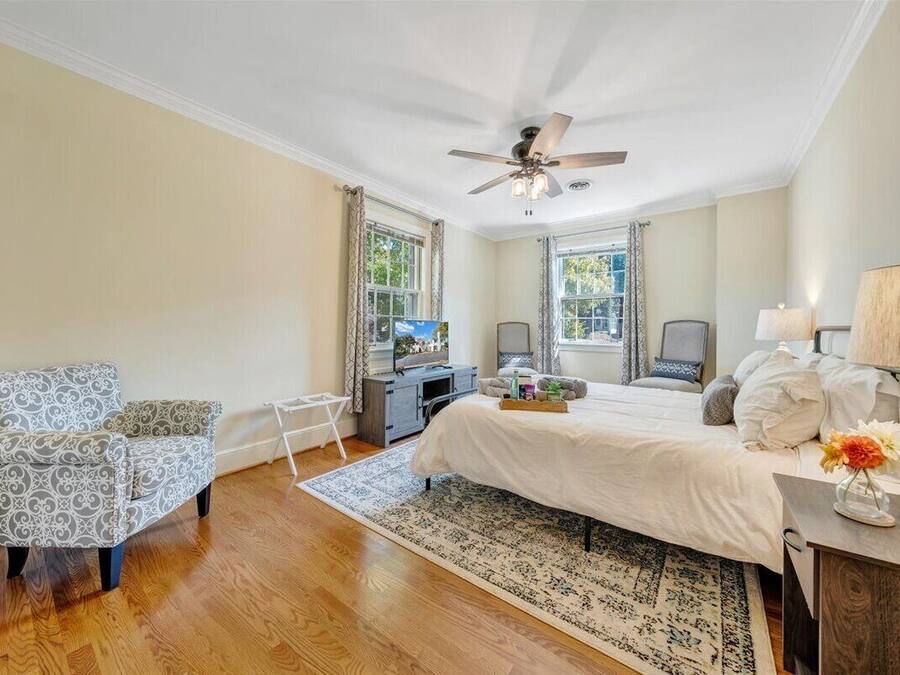 A bedroom with a bed, a chair, a desk, and a ceiling fan.