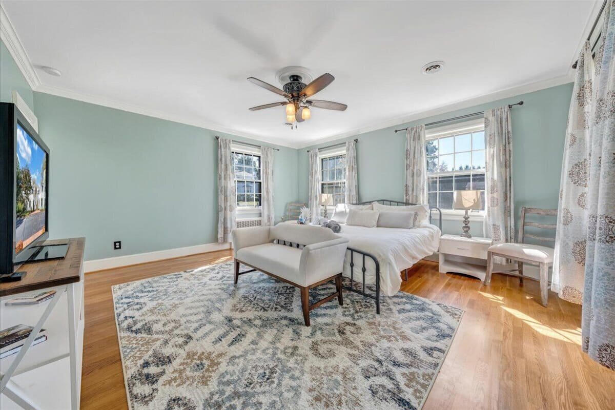 A bedroom with a bed, a chair, a desk, and a television.
