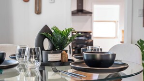 Une table à manger moderne, agrémentée de verres transparents, de bols noirs et d’une plante en pot.