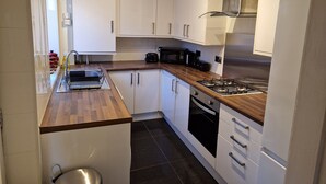 Une cuisine moderne avec des meubles blancs, un plan de travail en bois, une cuisinière et un évier.