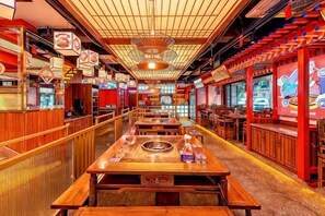 Un restaurant avec des tables et des bancs en bois, un long comptoir et un plafond haut avec un ventilateur.