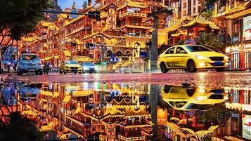 Una strada ben illuminata con riflessi nell'acqua, un taxi giallo e architettura tradizionale.