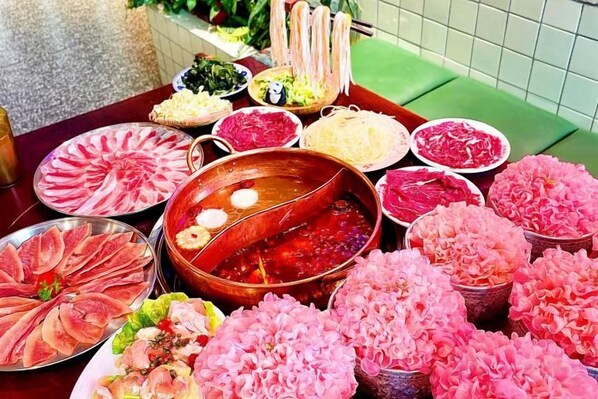 A table with various food items including a hot pot, seafood, and flowers.