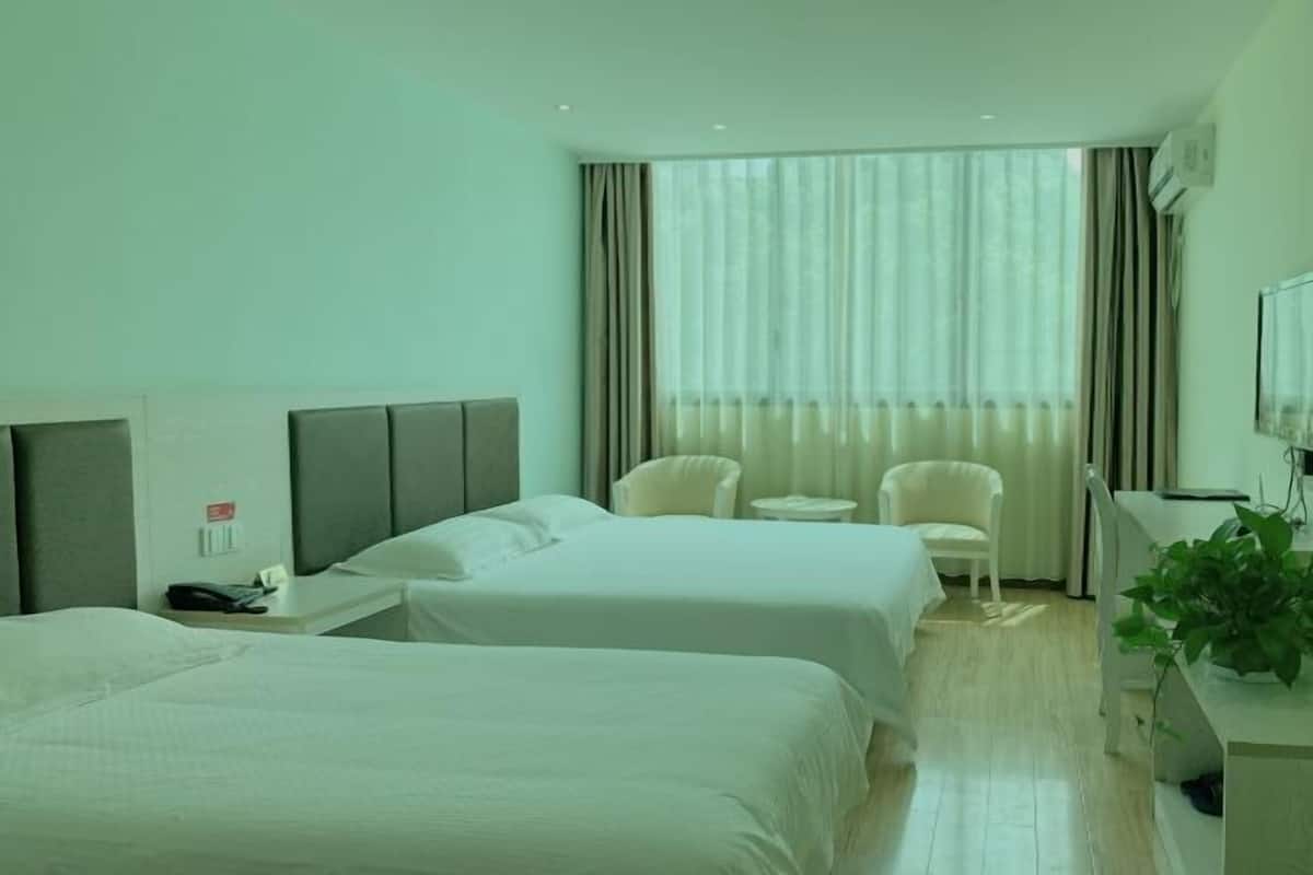 Een hotelkamer met twee bedden, een bureau, een stoel, een tafeltje en een televisie.
