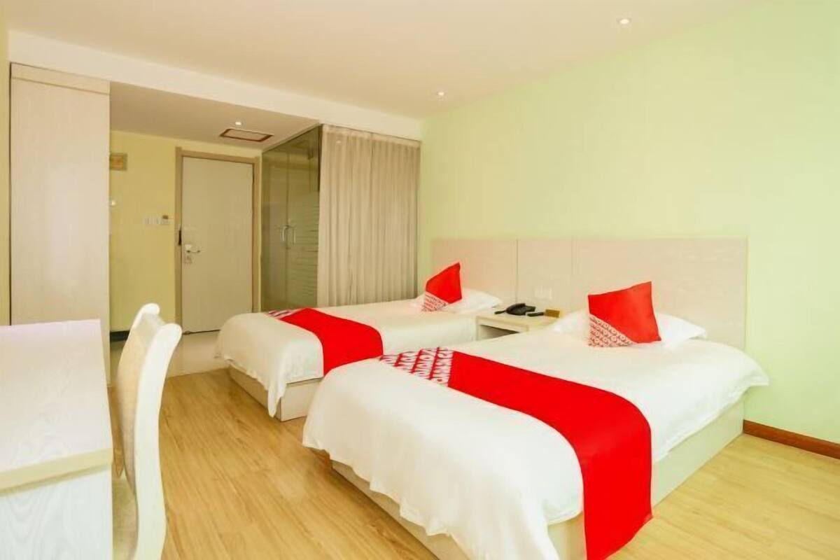 Een hotelkamer met twee bedden, een bureau en een stoel.