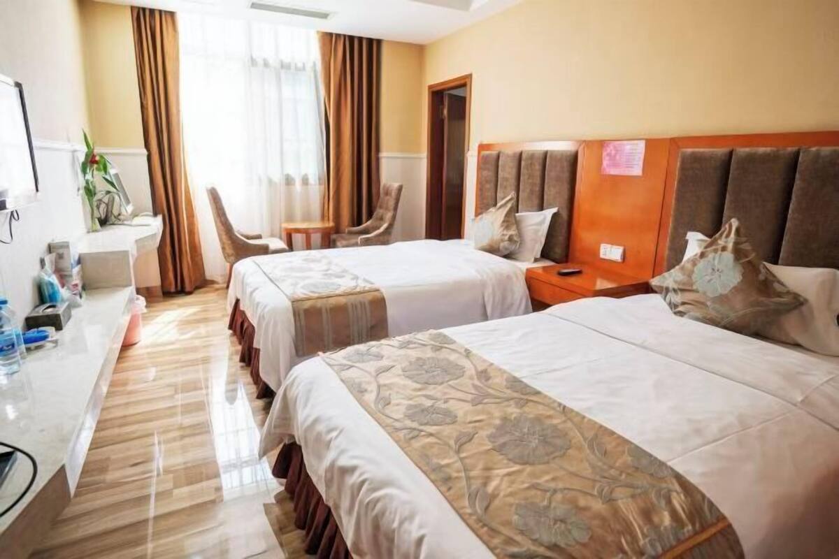 Ein Hotelzimmer mit zwei Betten, einem Schreibtisch, einem Stuhl und einem kleinen Tisch.