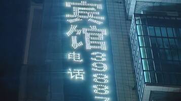 A building with a vertical sign displaying numbers and Chinese characters, likely indicating a hotel or business address.