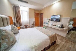 Una habitación de hotel con una cama grande, un televisor, un escritorio con una silla y una mesita.