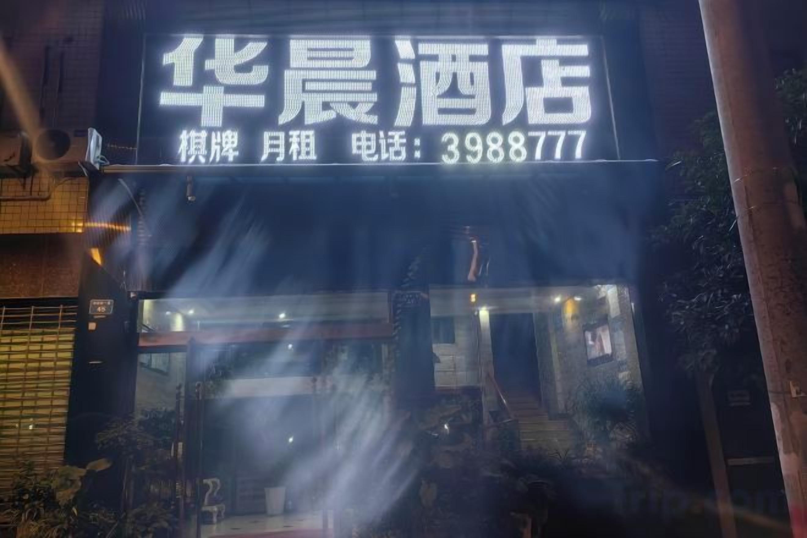 A hotel sign with the name '华晨酒店' and a phone number '3988777'.
