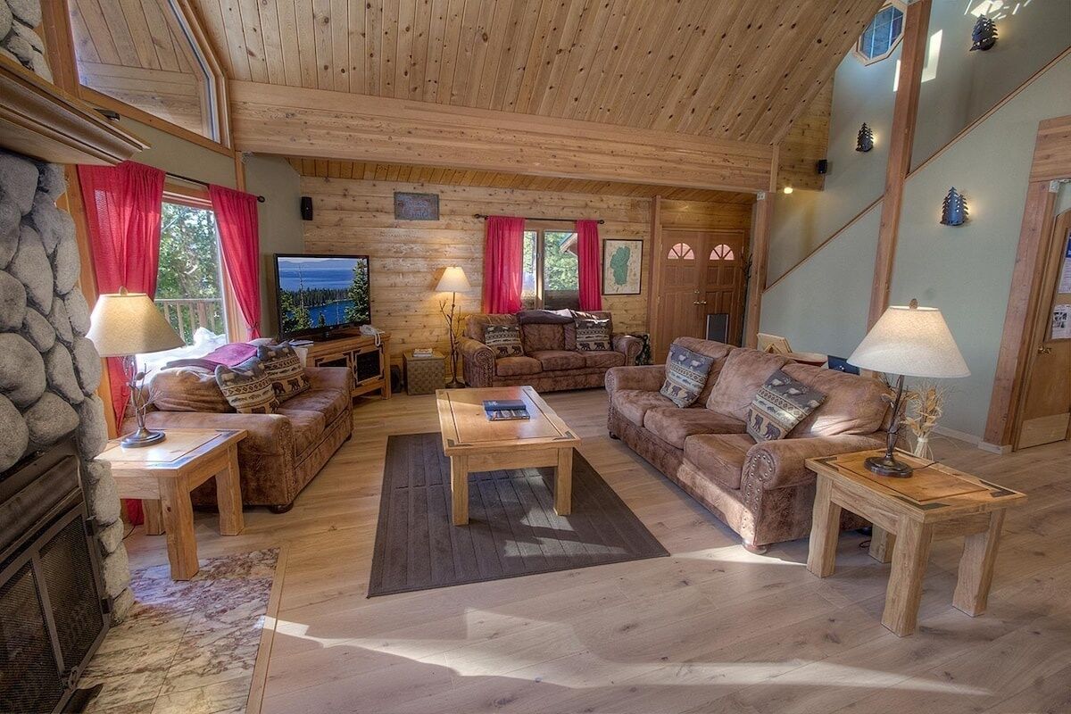 Accogliente interno di una baita in legno con camino, arredi in legno e televisore.