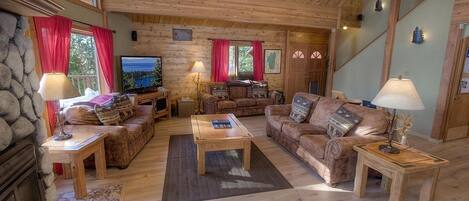 Accogliente interno di una baita in legno con camino, arredi in legno e televisore.