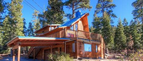 A wooden cabin with a balcony, a covered porch, and a staircase leading to the upper level.