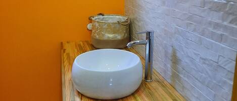 A bathroom with a white sink, a wooden vanity, a mirror, and a window.