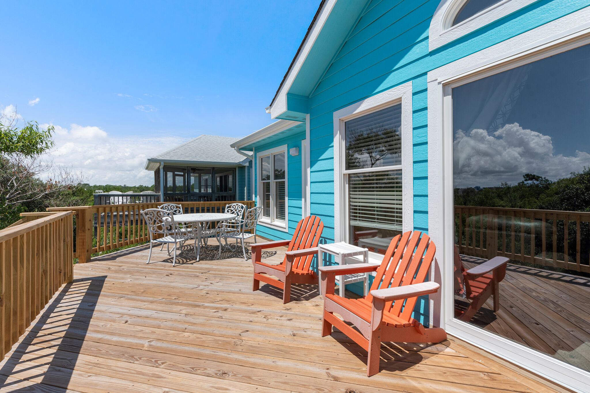 Une terrasse avec un plancher en bois, des meubles d’extérieur et une vue sur un immeuble bleu doté de grandes fenêtres.